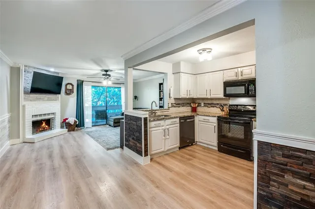 a kitchen with granite countertop a stove top oven a sink dishwasher and a fireplace with wooden floor
