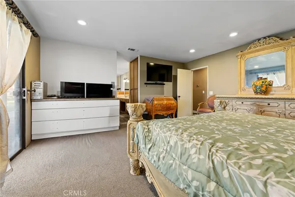 a bedroom with a bed a flat screen tv and kitchen view