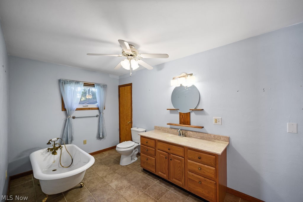 11363 Dupont Road Washington, WV 26181 - Photo 15 of 42 Free-standing clawfoot tub, wood-finish vanity with an integrated sink, built-in wall mirror, overhead ceiling fan, and tiled flooring