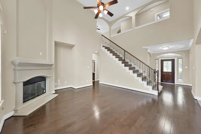 a view of an empty room with wooden floor a fireplace and a window
