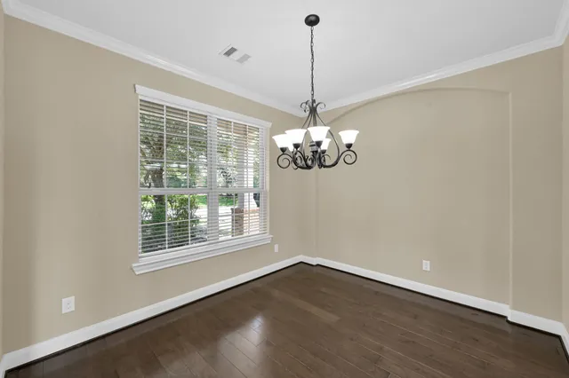a view of a room with wooden floor chandelier and windows