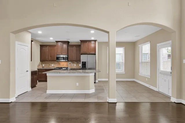 a view of a kitchen with kitchen island a sink stainless steel appliances and cabinets