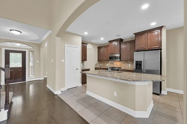 a large kitchen with stainless steel appliances granite countertop a lot of counter space and wooden floor