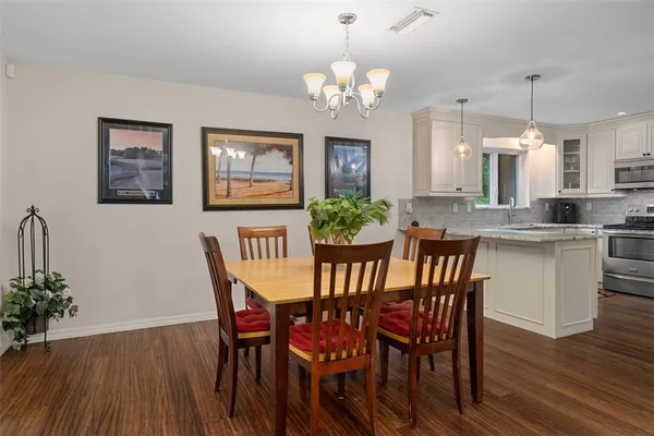 a kitchen with stainless steel appliances granite countertop a sink a stove a refrigerator and white cabinets with wooden floor