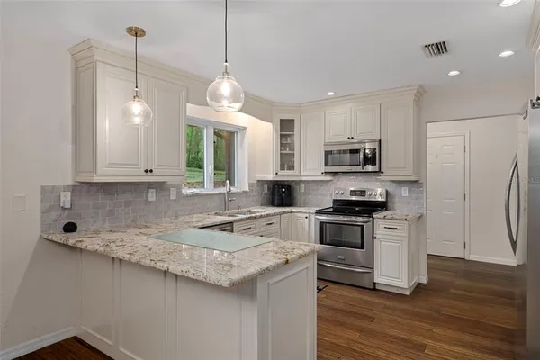 a kitchen with stainless steel appliances granite countertop a sink a stove and a microwave