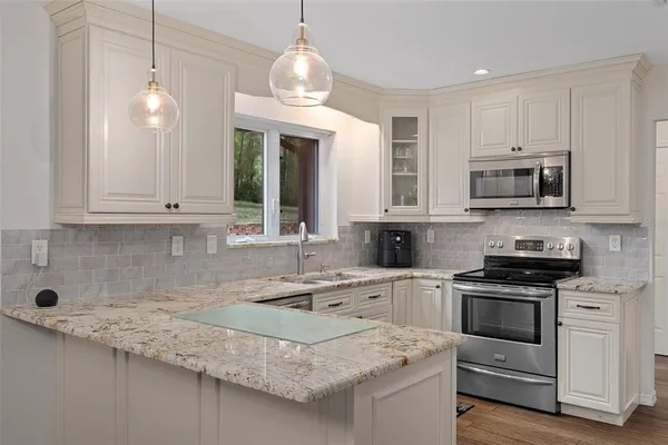 a kitchen with granite countertop a sink window and cabinets