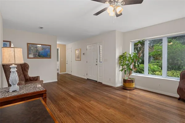 a view of a livingroom with a potted plant a ceiling fan and wooden floor