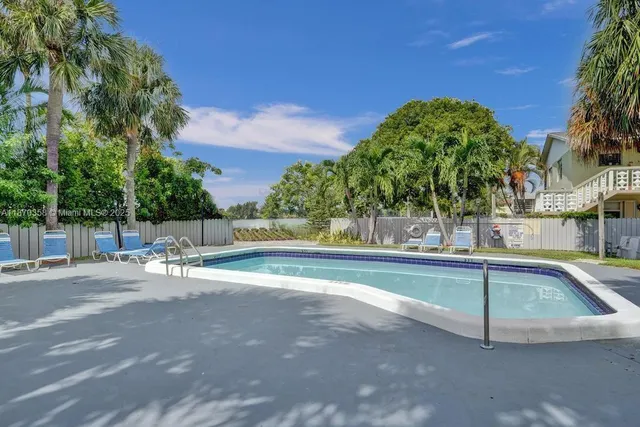 a view of swimming pool with outdoor seating and house in the background