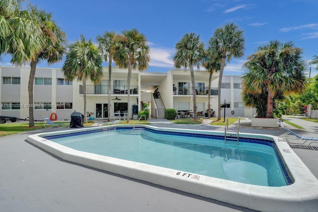 900 Crystal Lake Drive, Unit 2B Deerfield Beach, FL 33073 - Photo 33 of 41 a view of swimming pool with outdoor seating and house in the background
