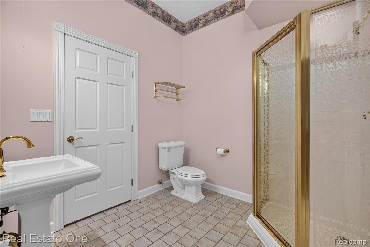 425 Courtney Road Leonard, MI 48367 - Photo 40 of 89 Bathroom featuring a pedestal sink with brass-finish faucet, a toilet, and a stand-up shower with a brass-finish framed enclosure