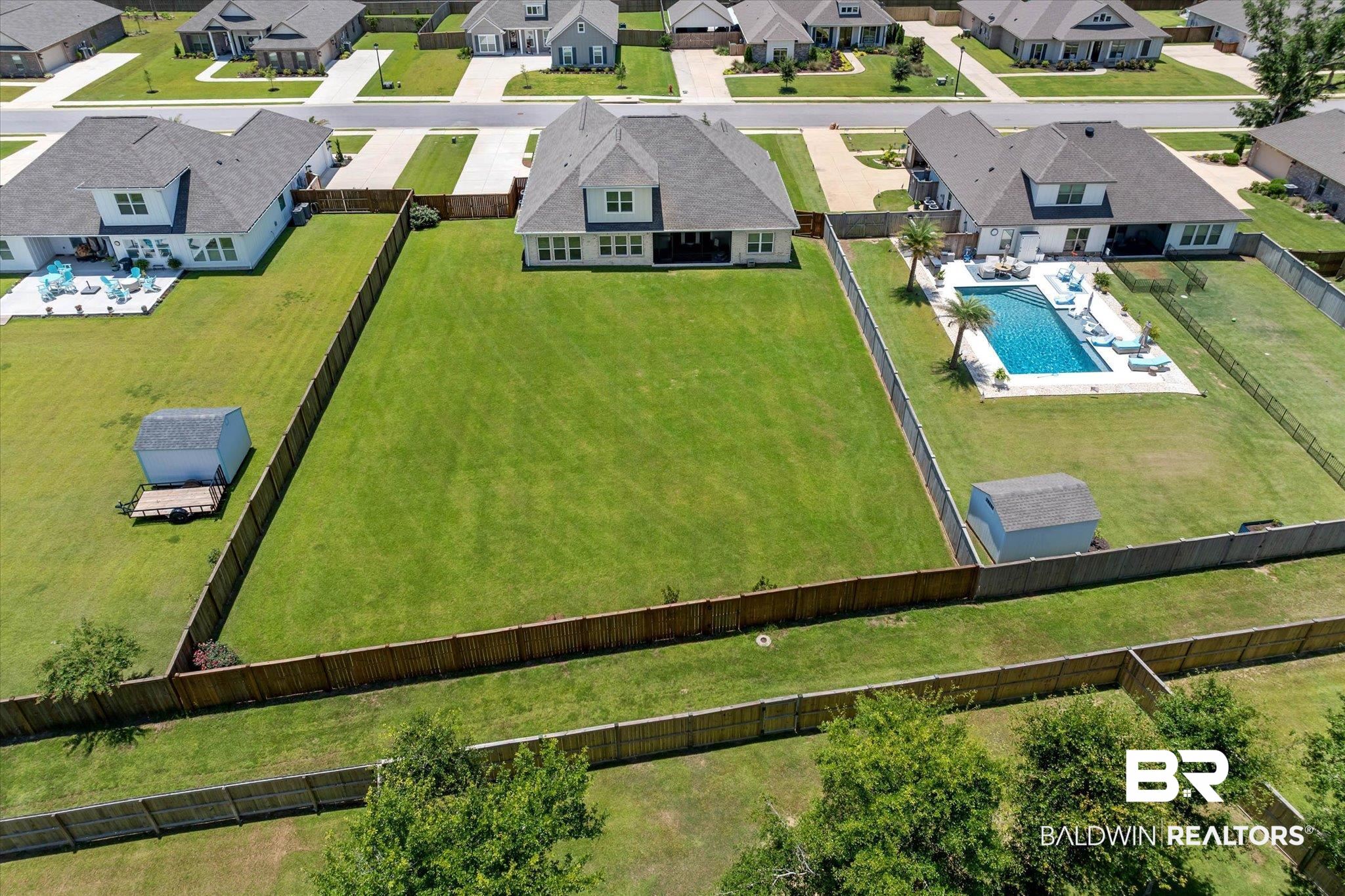23523 Travis Stock Street Foley, AL 36535 - Photo 38 of 45 Expansive backyard featuring a large green lawn, full privacy fencing, and a detached shed