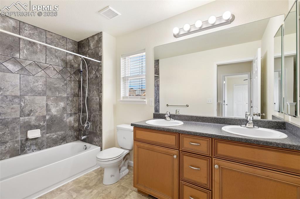 7678 Dutch Loop Colorado Springs, CO 80925 - Photo 22 of 29 a bathroom with a granite countertop sink a toilet a mirror a bathtub and shower