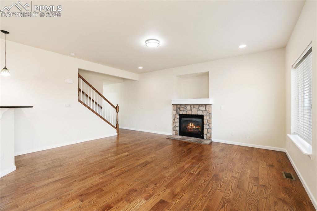 7678 Dutch Loop Colorado Springs, CO 80925 - Photo 4 of 29 a view of empty room with wooden floor and fireplace