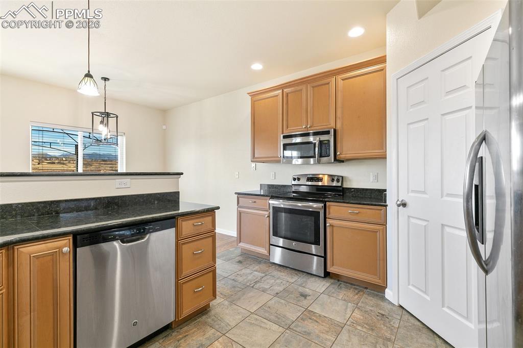 7678 Dutch Loop Colorado Springs, CO 80925 - Photo 8 of 29 a kitchen with stainless steel appliances granite countertop a stove a sink and a refrigerator