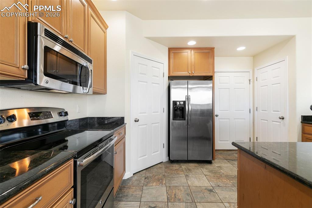 7678 Dutch Loop Colorado Springs, CO 80925 - Photo 9 of 29 a kitchen with stainless steel appliances granite countertop a stove a microwave and a refrigerator