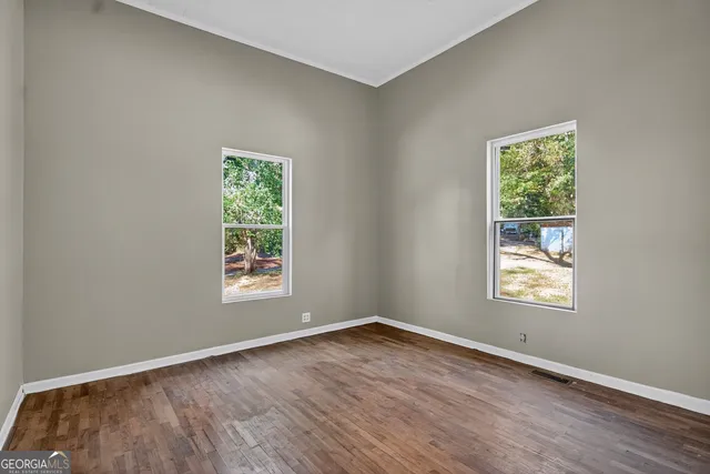 an empty room with wooden floor and windows