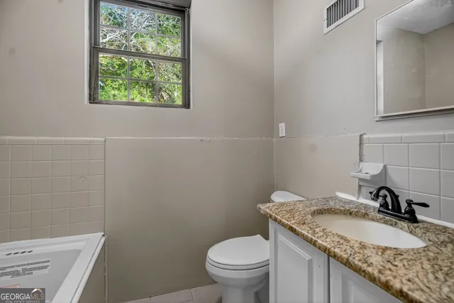 a bathroom with a granite countertop toilet sink and mirror