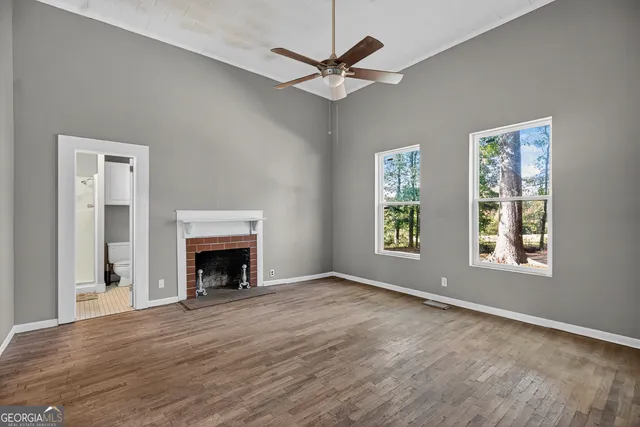 an empty room with windows a fireplace and a ceiling fan