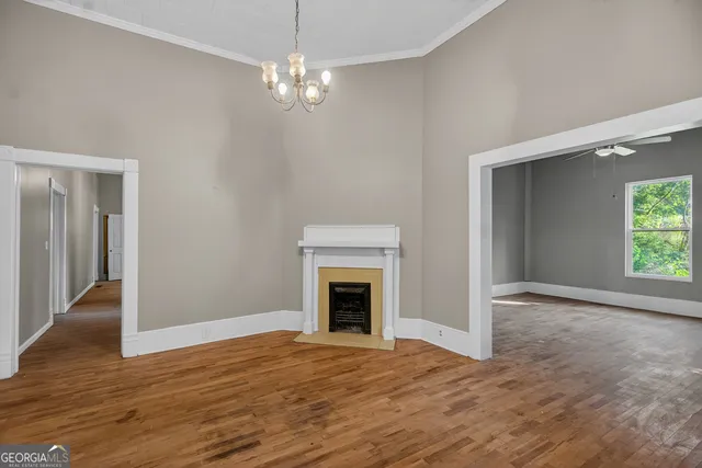 a view of an empty room with wooden floor and fireplace