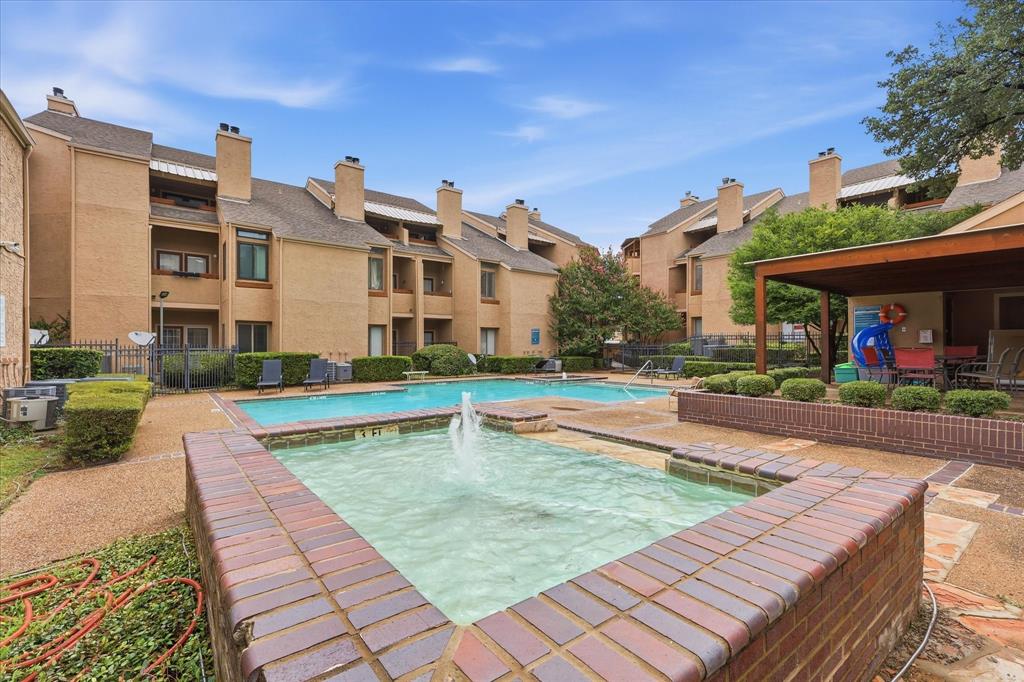 5550 Spring Valley Road, Unit A31 Dallas, TX 75254 - Photo 20 of 24 Community pool area featuring a brick-lined fountain, a swimming pool with a 3-foot depth marker, a covered patio structure, and surrounding mature landscaping