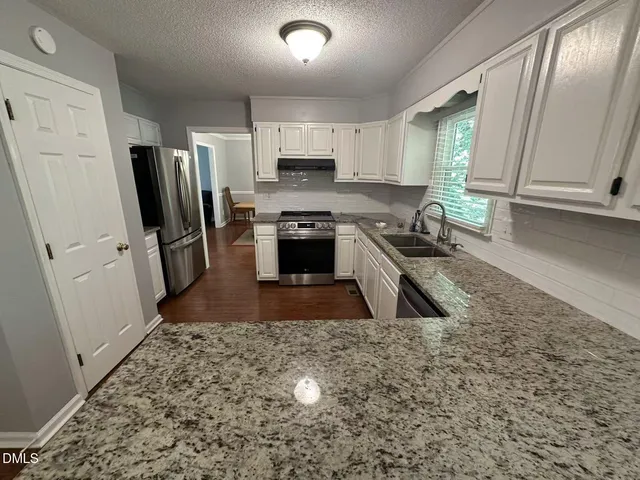 a kitchen with granite countertop a refrigerator a sink a stove a microwave and island
