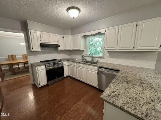 a kitchen with stainless steel appliances granite countertop a stove a sink dishwasher and a microwave oven with wooden floor