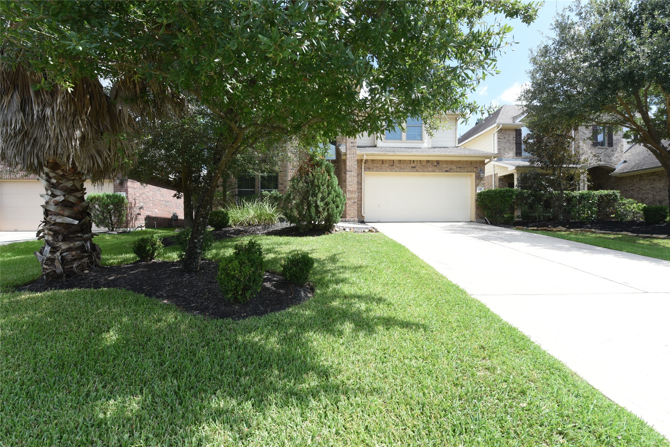 Charming two-story home with a spacious driveway and lush landscaping, nestled in a serene neighborhood in The Woodlands.
