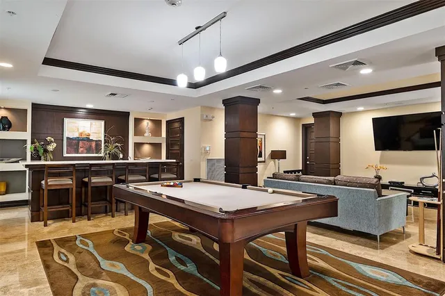 a room with furniture pool table flat screen tv and windows