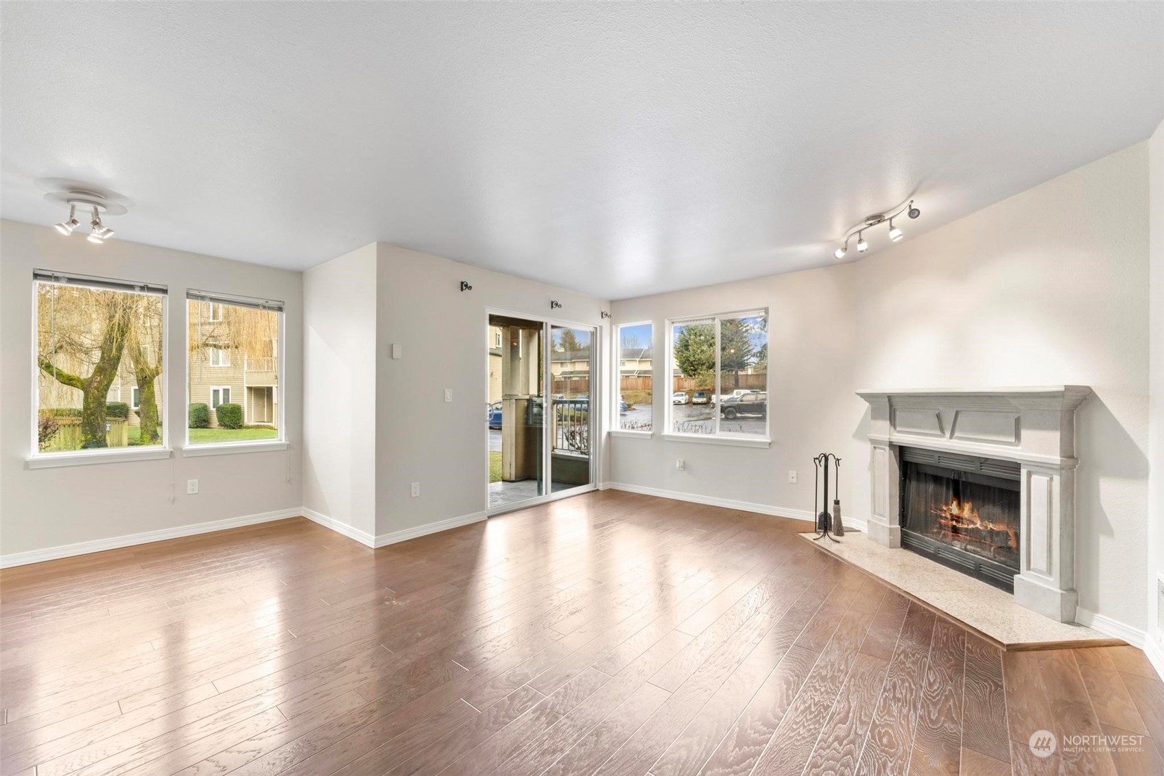 20328 Bothell Everett Highway, Unit B101 Bothell, WA 98012 - Photo 3 of 25 an empty room with windows a fireplace and wooden floor