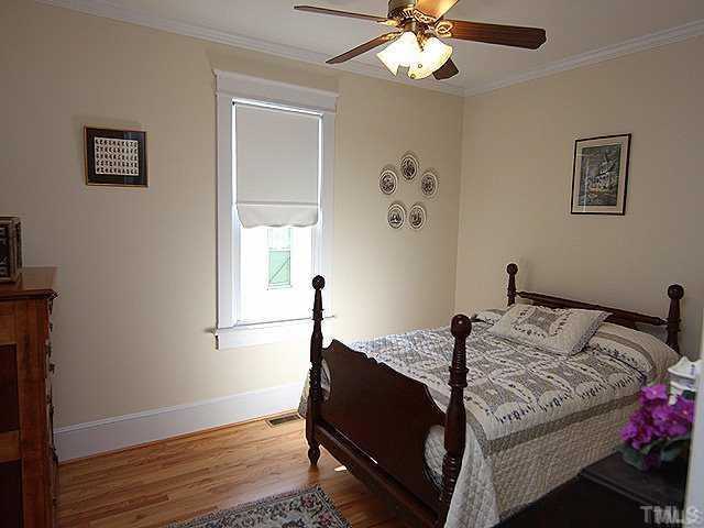 103 Georgetown Road Raleigh, NC 27608 - Photo 8 of 12 a bedroom with a bed and wooden floor