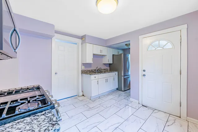a kitchen with a stove a refrigerator and white cabinets