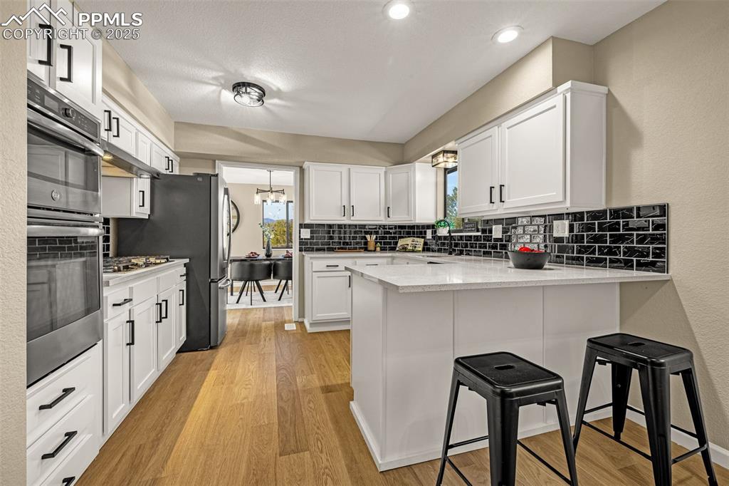23 Newport Circle Colorado Springs, CO 80906 - Photo 12 of 49 a kitchen with stainless steel appliances a refrigerator a stove a sink dishwasher and white cabinets with wooden floor