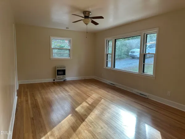 a view of empty room with wooden floor and fan