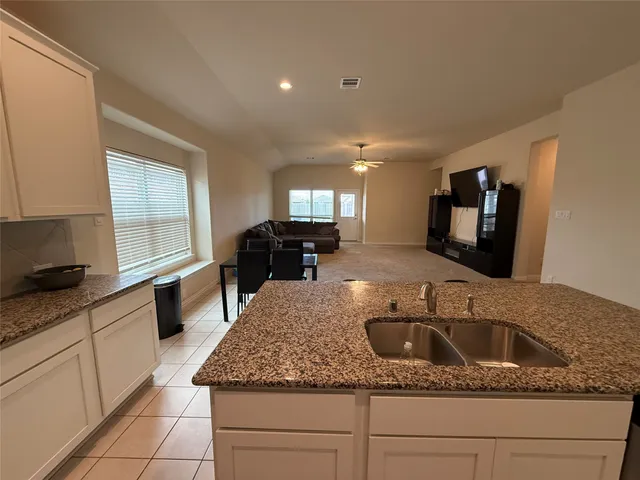 a kitchen with granite countertop a sink a stove and cabinets