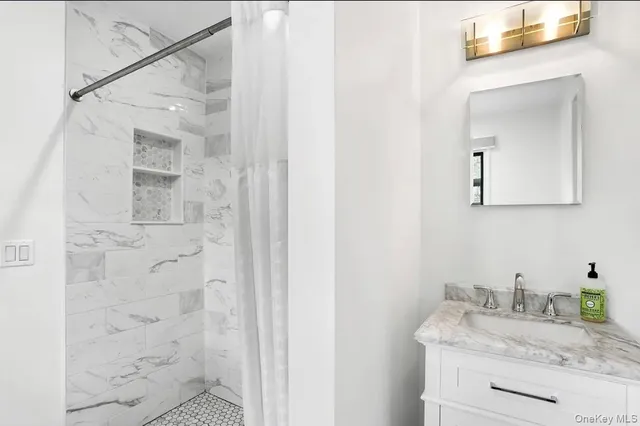 a bathroom with a granite countertop sink a mirror and shower