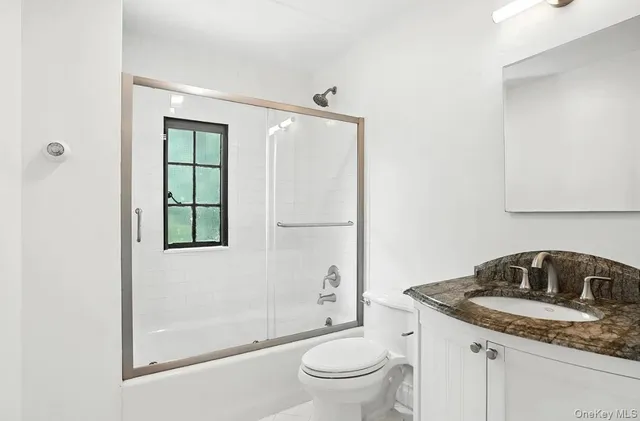 a bathroom with a granite countertop sink toilet and shower