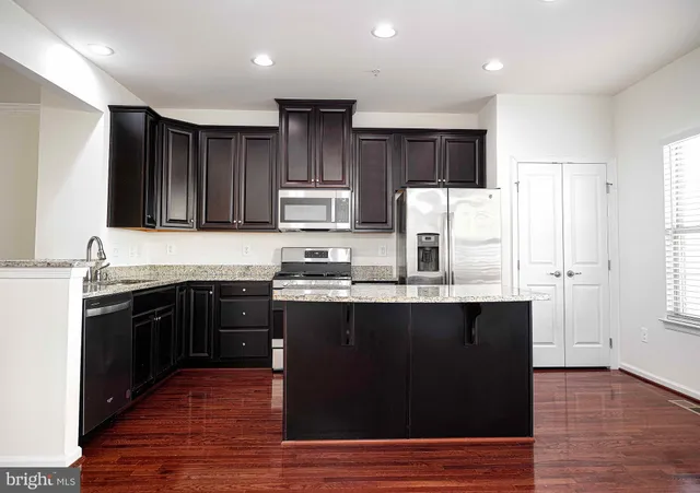 a kitchen with kitchen island granite countertop a sink stove and refrigerator