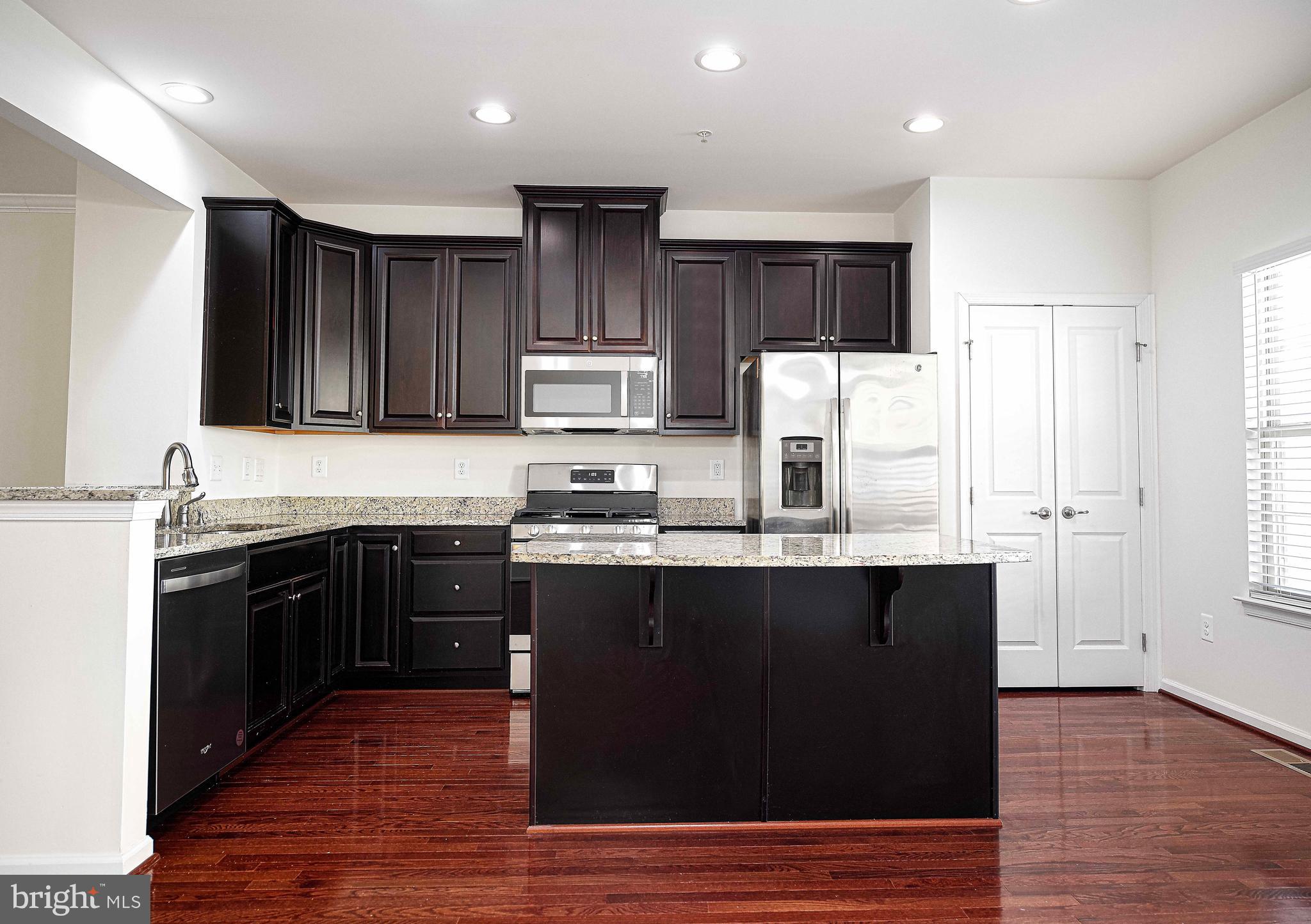 1032 Ramble Run Road Baltimore, MD 21220 - Photo 13 of 46 a kitchen with kitchen island granite countertop wooden floors stainless steel appliances and cabinets