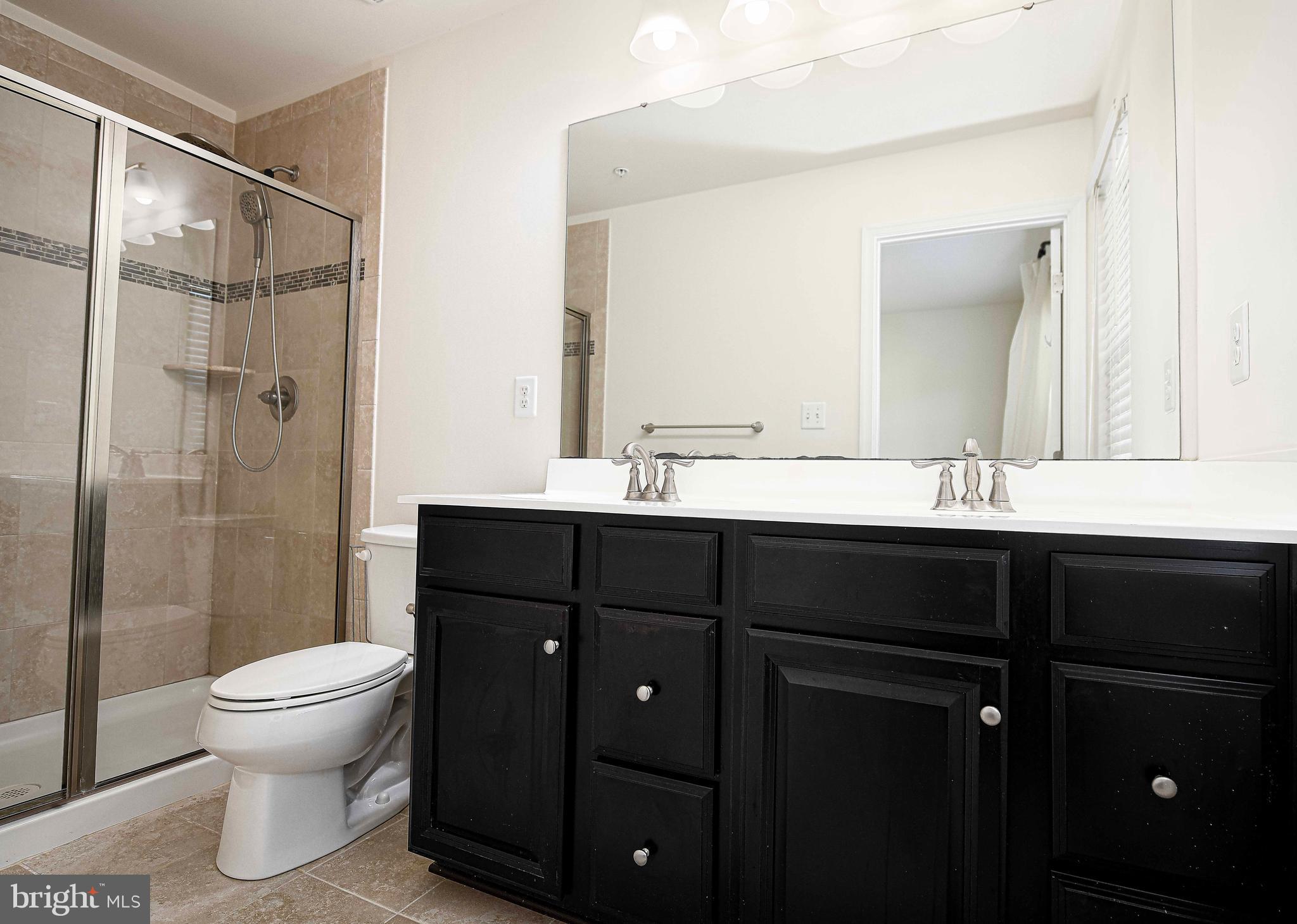 1032 Ramble Run Road Baltimore, MD 21220 - Photo 22 of 46 a bathroom with a double vanity sink toilet and shower
