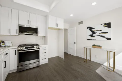 a kitchen with stainless steel appliances white cabinets and a stove top oven