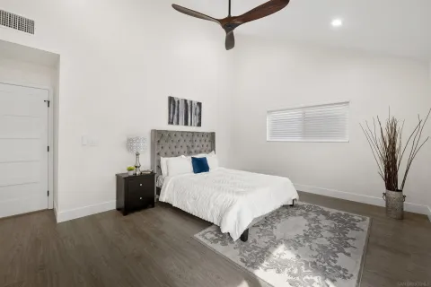 a bedroom with a bed and a potted plant on the dresser