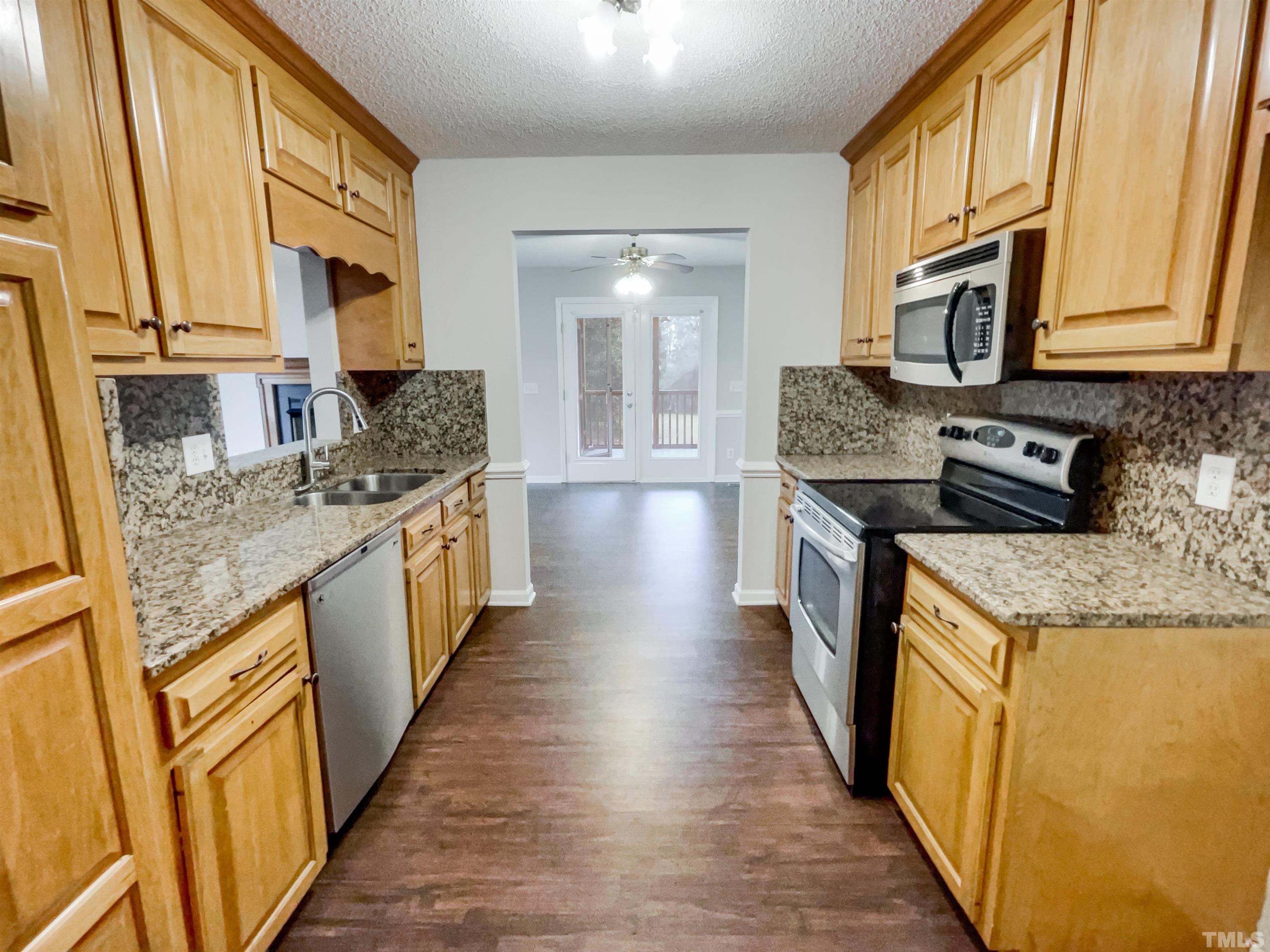 1459 Atkins Road Fuquay-Varina, NC 27526 - Photo 11 of 21 a kitchen with stainless steel appliances granite countertop a stove a sink and a microwave