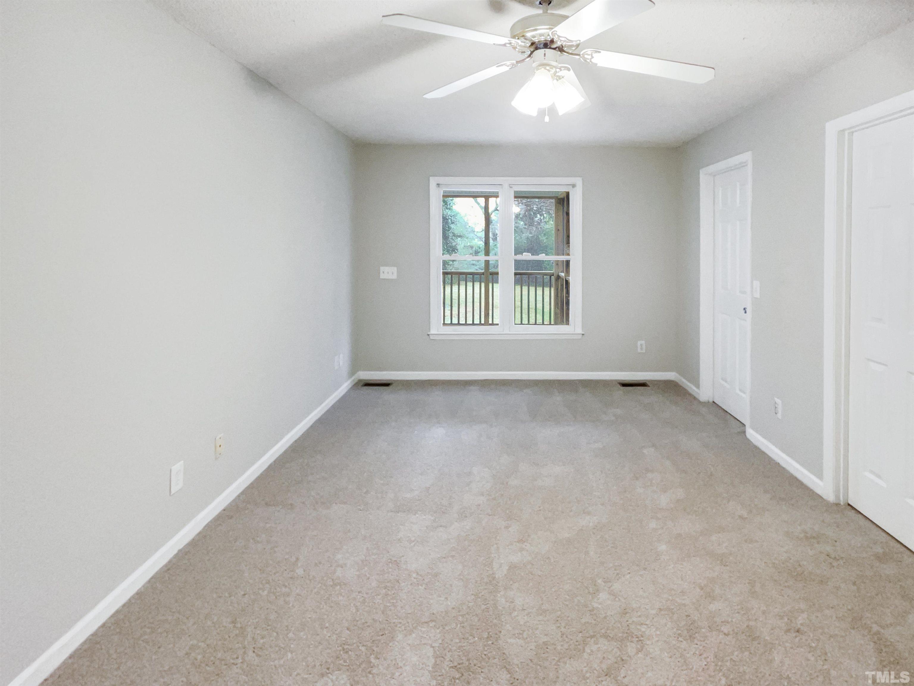 1459 Atkins Road Fuquay-Varina, NC 27526 - Photo 17 of 21 an empty room with a chandelier fan and windows