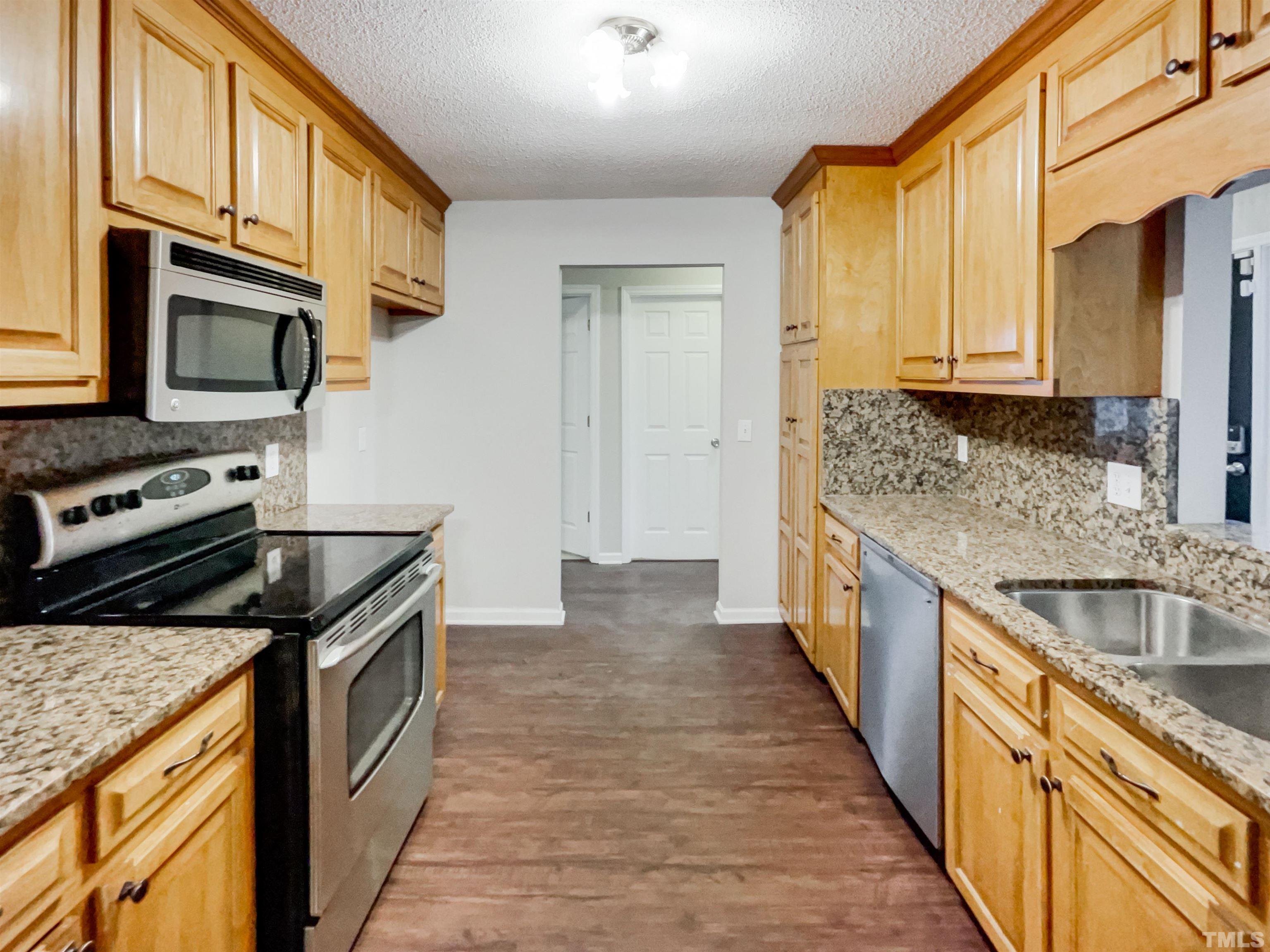 1459 Atkins Road Fuquay-Varina, NC 27526 - Photo 10 of 21 a kitchen with stainless steel appliances granite countertop a stove a sink and a microwave