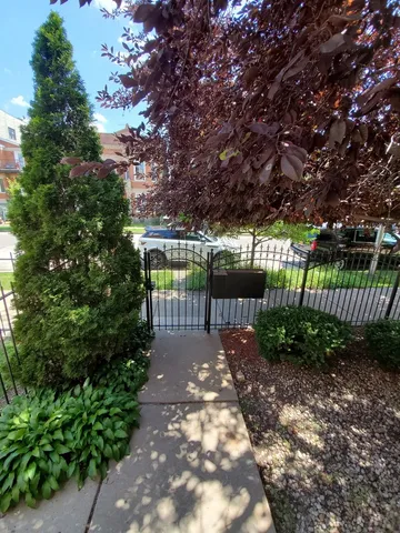 a view of a pathway with a wrought fence next to a yard