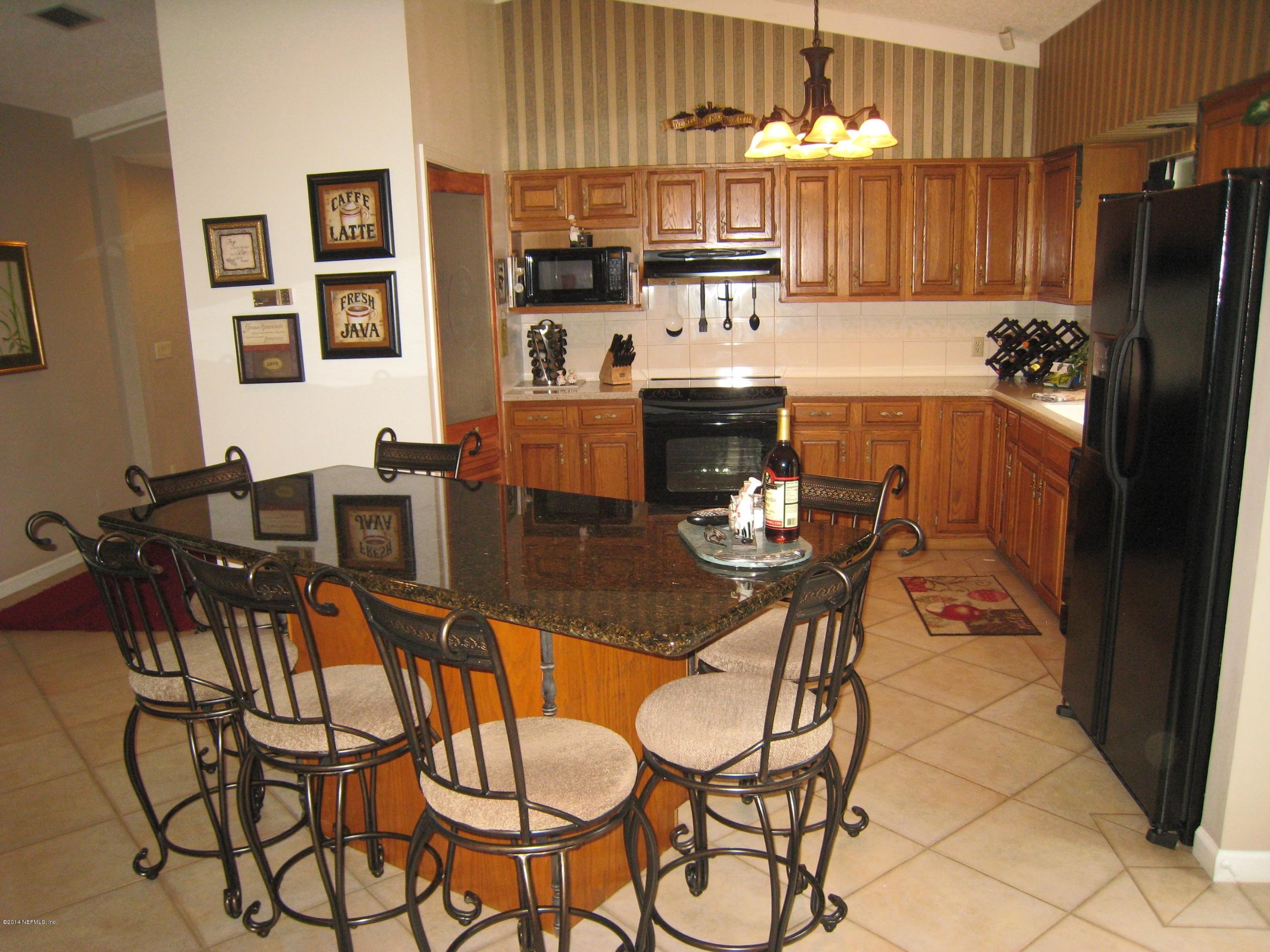 11636 Mandarin Road Jacksonville, FL 32223 - Photo 13 of 41 a kitchen with stainless steel appliances kitchen island granite countertop a dining table chairs and a refrigerator