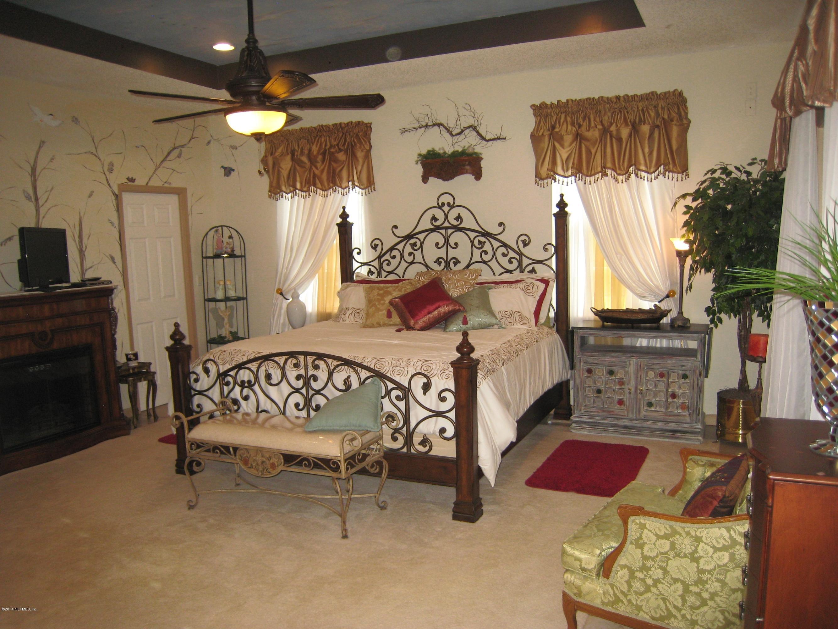 11636 Mandarin Road Jacksonville, FL 32223 - Photo 19 of 41 a bedroom with a bed a mirror on dresser and a chandelier