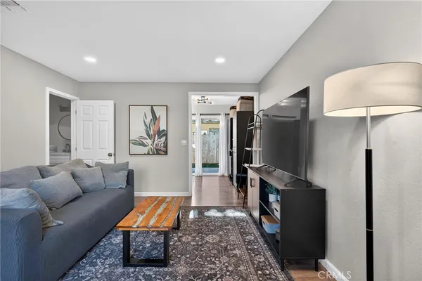 a living room with furniture a flat screen tv and a refrigerator
