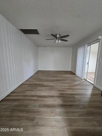 a view of empty room with wooden floor and ceiling fan
