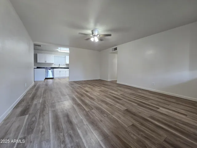 a view of empty room with wooden floor and fan